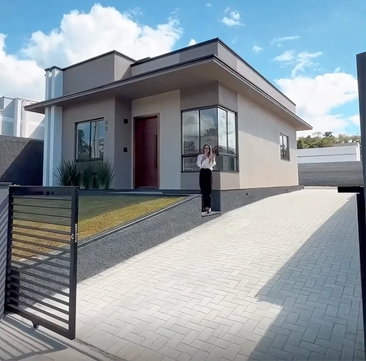 Cliente em frente à casa moderna com portão e entrada pavimentada